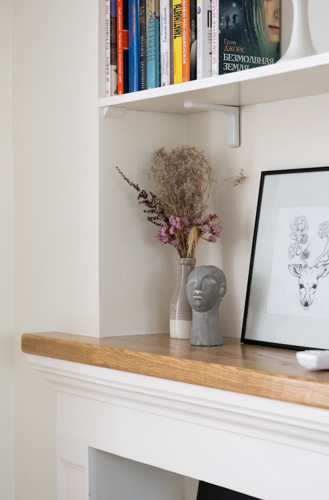 Minimalist interior featuring a bookshelf, art, and dried floral decor.